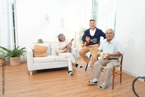 A group of elderly men and women, grandmothers and grandfathers, happily participate in activities together, singing songs and playing guitars in the nursing home.
