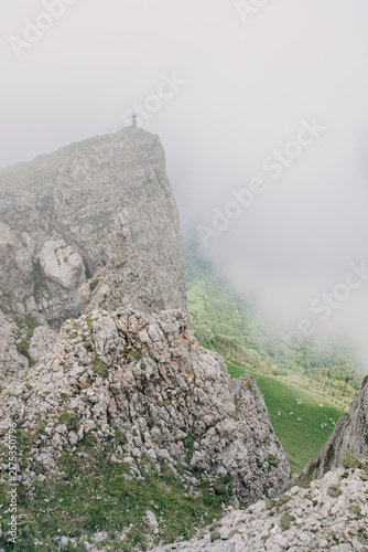 Quadro su tela Mountain ridge and dramatic cliffs rising above clouds on a moody summer day