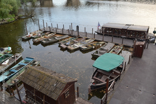 Фотография Riverside dock with multiple moored wooden boats and covered skiff for travel ba