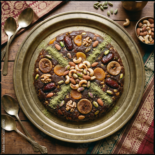 Traditional dry fruit halwa garnished with cardamom powder and roasted nuts on a brass platter