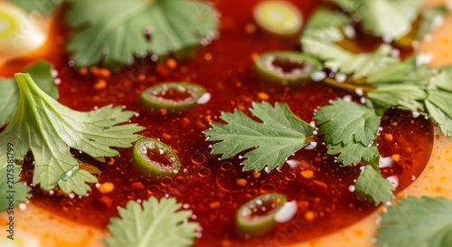 Close up of vibrant chili oil with herbs and scallions on transparent background