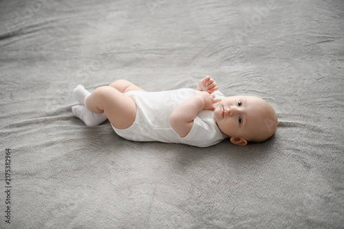 Cuadro en lienzo Full length view of adorable baby boy lying on back on spacious grey blanket, looking at camera with curiosity in bright minimalist interior