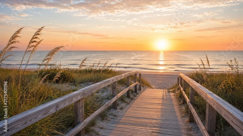 Coastal sunrise over wooden boardwalk, beach path leading to ocean at dawn, serene tropical landscape with sea oats