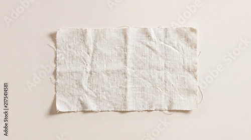 A piece of white fabric lies on a plain background, showcasing its texture and simplicity.
