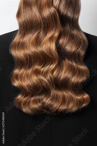 Back image of a long brown wavy hair of a woman.