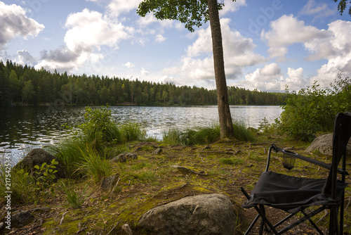 A lonely broken fishing chair by a forest lake