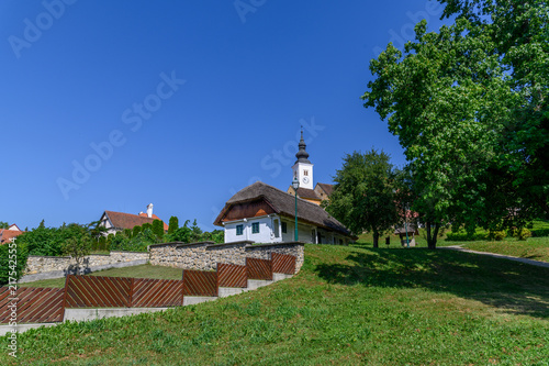 Canvas Print Traditional thatched cottage below the baroque onion domed church tower on a gre