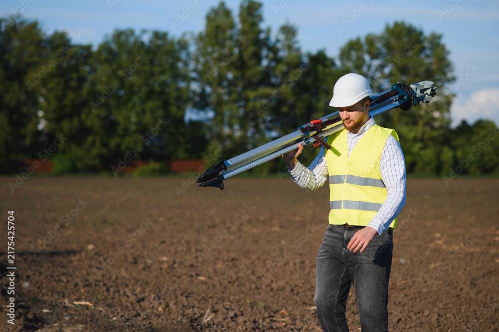 Fototapeta premium Land surveyor carrying geodetic equipment for field work