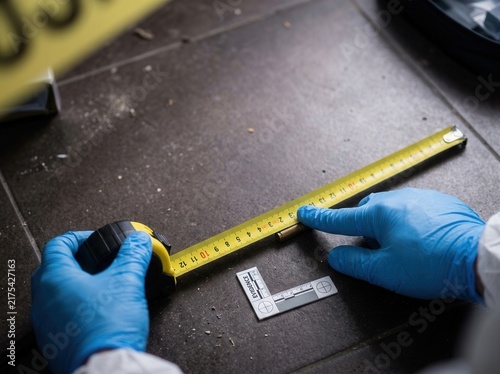 Crime Scene Investigation Measuring Evidence With Gloves And Tape Measure