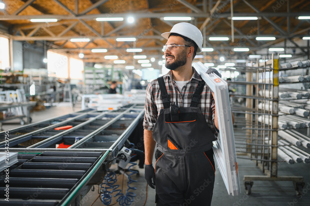 Fototapeta premium Worker carrying pvc window frame in plastic factory