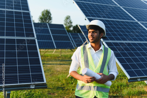 Konstfotografi Indian engineer holding blueprints establishing solar power plant