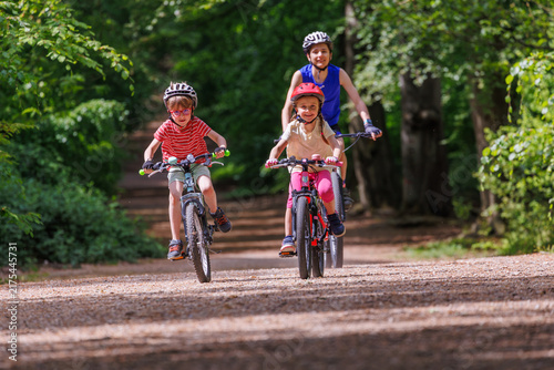 Group of children training riding bicycles along a wooded trail