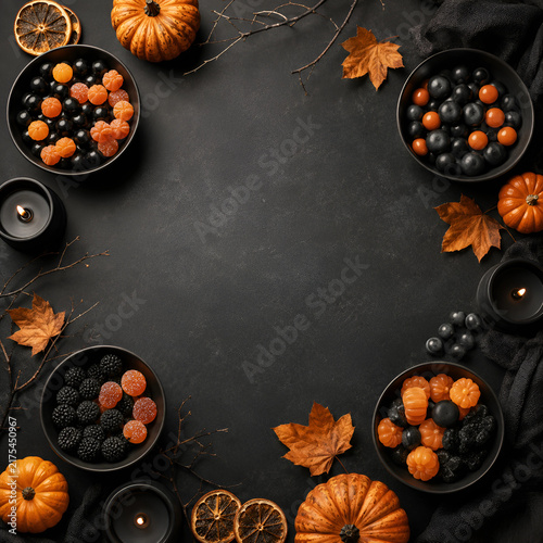  A home kitchen is decorated with pumpkins, black candles and fall branches. Pumpkin-shaped cookies on a wooden island create a warm scene for a seasonal tea party.