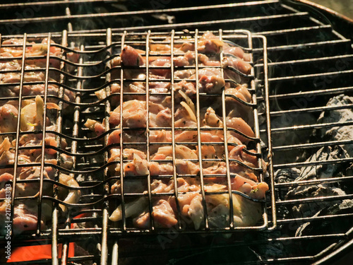 Canvastavla Two metal grills hold skewered chicken pieces over smoky charcoal