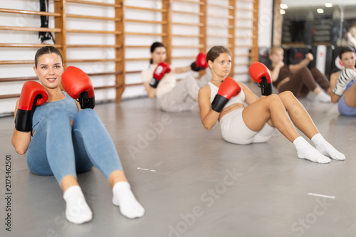Cuadro en lienzo Assertive woman attendee of boxing classes lying in press position with others i