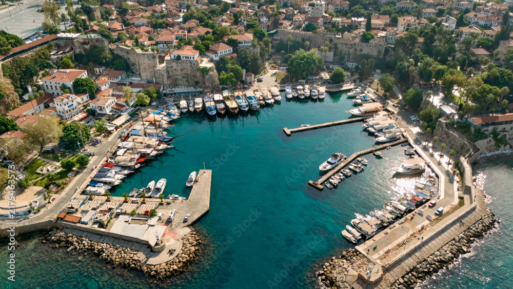 Obraz premium Aerial view of Kaleici harbor in Antalya with marina boats, turquoise water, historic stone walls and red tile rooftops in Turkey
