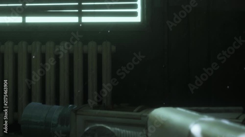 Light shines through slatted blinds in a dim room. A wall heater is visible below the window. Dust particles float in the air, adding to the atmosphere of the space.