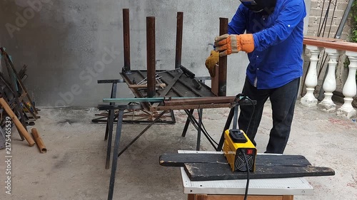 Welder using ceramic tile square tool to check right angle on metal leg
