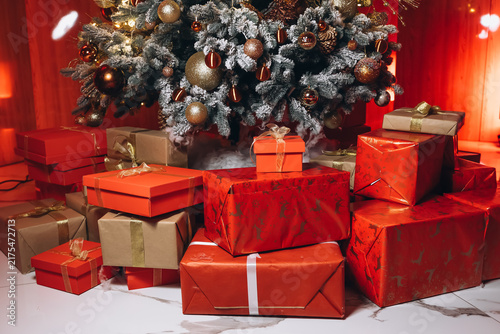 Obraz na plátně Christmas Tree and Gifts Galore: A beautifully decorated Christmas tree stands tall, surrounded by a generous pile of red-wrapped gifts, evoking the festive spirit and warmth of holiday celebrations