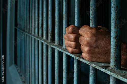 Obraz na płótnie prisoner's hands behind bars with black background