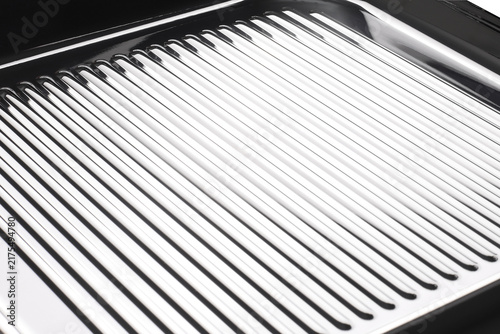 Shiny metal grill pan with raised ridges for cooking and searing food
