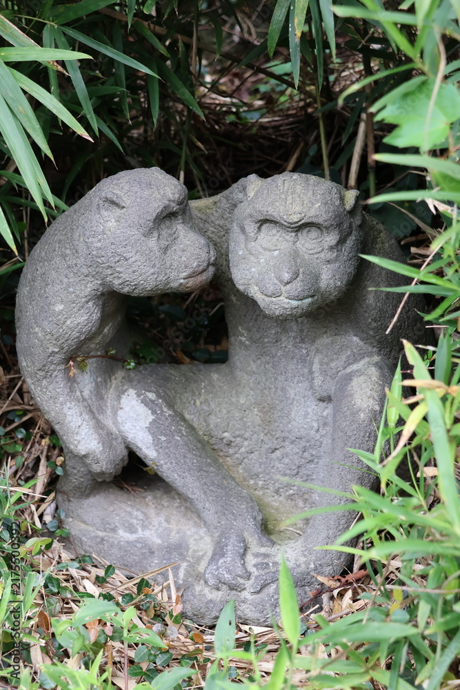 Fototapeta premium Two stone monkey statues in the roadside grass