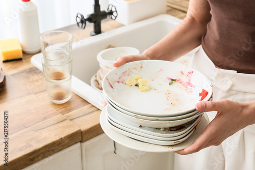 Cuadro en lienzo Household chores and domestic burden, person holding a stack of dirty dishes in