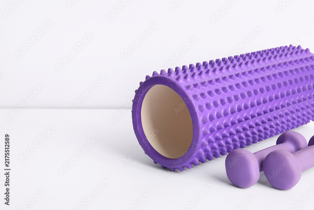 Obraz premium Foam roller with dumbbells on white background