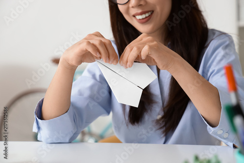 Young businesswoman with paper plane at home, closeup
