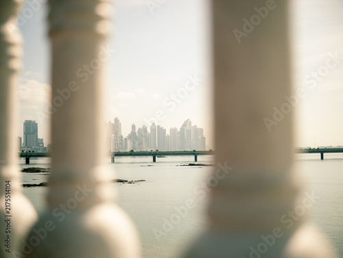 Fotografie Sunlight illuminates the distant cityscape over calm water