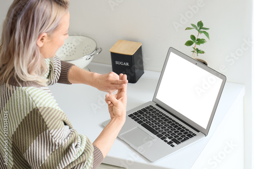 Mature mute woman using sign language during video call at home