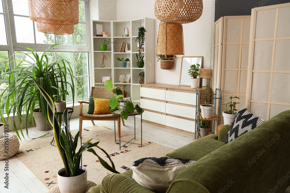 Naklejka premium Interior of living room with houseplants, armchair and shelf unit