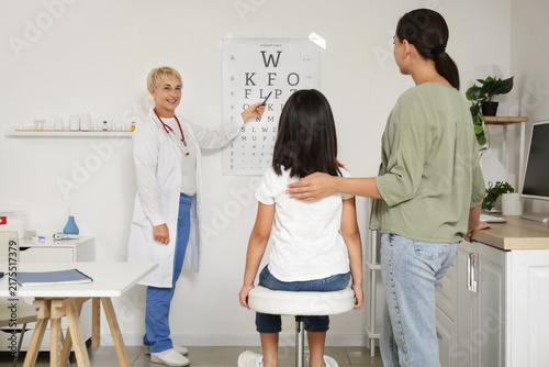 Foto Female pediatrician checking little girls eyesight and mother in clinic