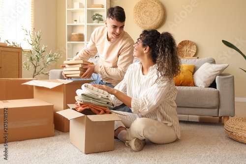 Happy young couple unpacking moving boxes at new home