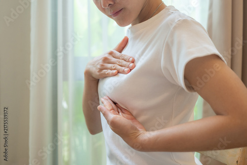 Cropped shot view of young Asian woman touching her breast for checking breast size or cancer awareness.