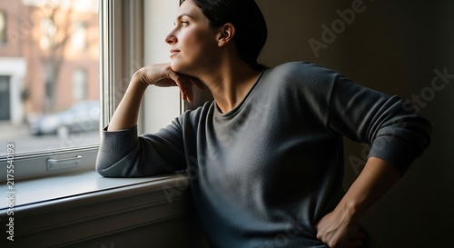 Woman lost in thought gazing out of the window with contemplative expression