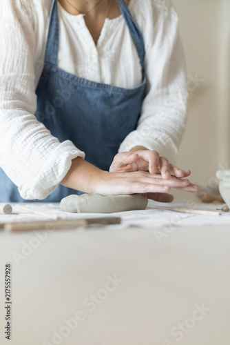 Potter artist forming clay in a focused and creative ceramic studio side view with white and gray tones and wooden tools, artistic hobby and crafting visual resource for web banners and posters.