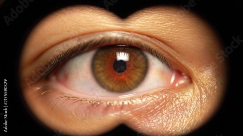 Human eye looking through binoculars creating a circular vignette frame