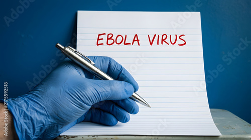 Gloved hand writing ebola virus on notepad in medical setting