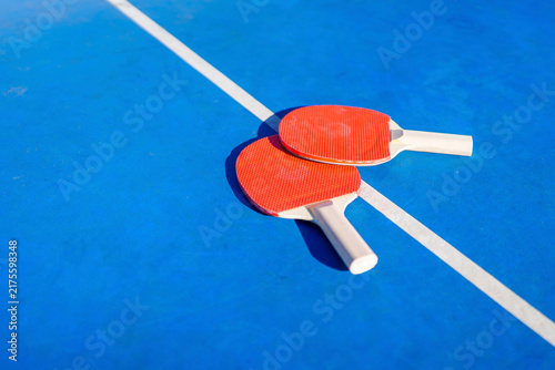 Two red ping pong rackets on blue table
