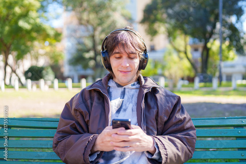 Young man enjoying music outdoors using smartphone