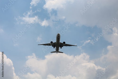 Konstfotografi Commercial airplane flying overhead against a cloudy blue sky
