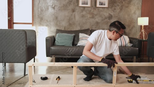 Asian forgetful man self-assembling furniture with DIY tools, forgetting and finding rubber mallet hammer, home improvement, expert craft installation, wooden hobby workshop, mature active lifestyle.