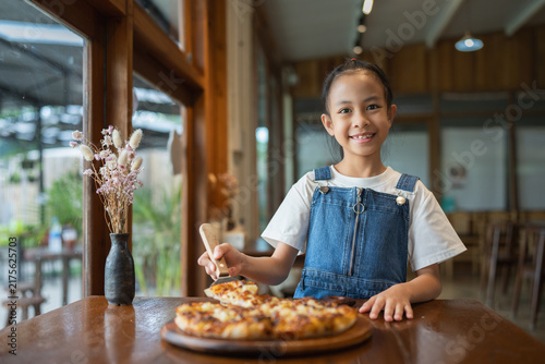 Photography Happy little girl serving pizza at restaurant