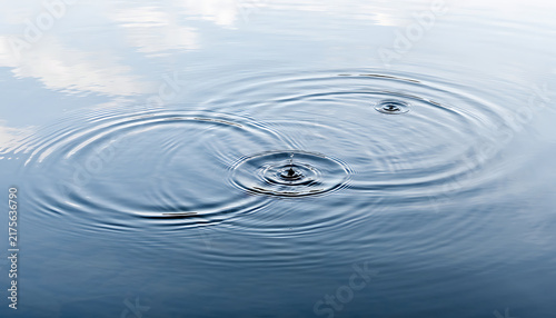 Concentric Water Ripples on Blue Surface with Droplet Impact and Sky Reflection