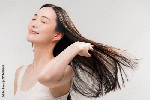 笑顔の日本人女性が長く美しい髪を手でなびかせている