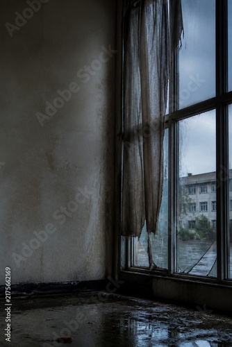 Abandoned hospital window and broken curtain after rain