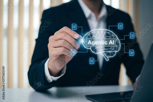 Businessman in a suit pointing at an agentic ai brain hologram with connected data files