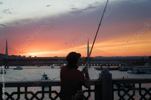 Fototapeta イスタンブールの夕焼けに浮かぶ釣り人のシルエットと橋