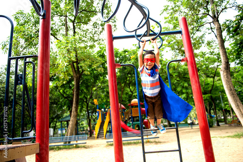 Canvastavla Child in superhero costume playing on monkey bars in a park.